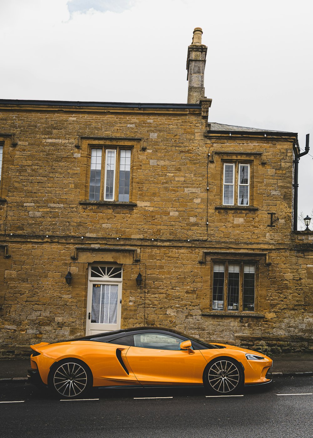 an orange sports car parked in front of a brick building