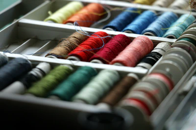 Close-up of colorful sewing threads and buttons neatly organized in small containers.