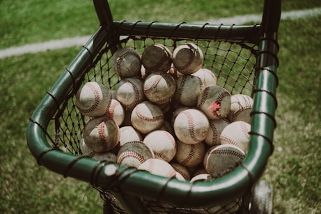 a basket full of baseballs sitting on the grass