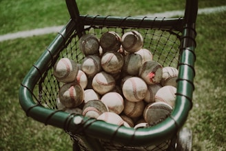 a basket full of baseballs sitting on the grass