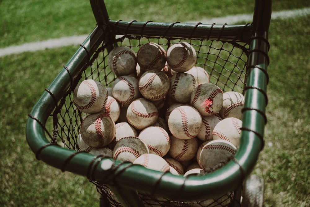 Un panier rempli de balles de baseball assis sur l’herbe