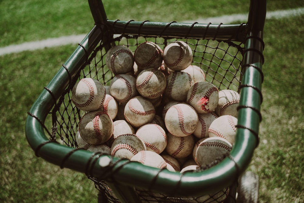a basket full of baseballs sitting on the grass