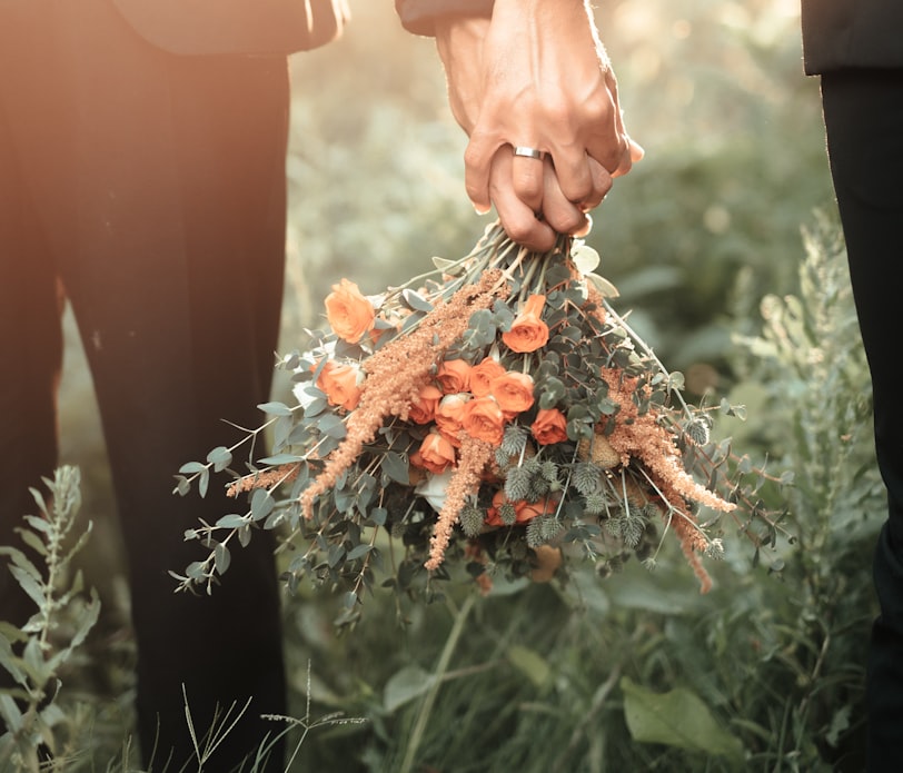 a couple of people holding a bouquet of flowers