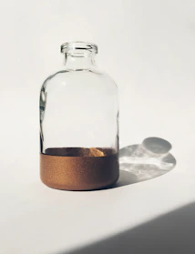 Elegant square glass jar filled with authentic Ibiza sand, placed on a smooth beige surface with soft natural light.