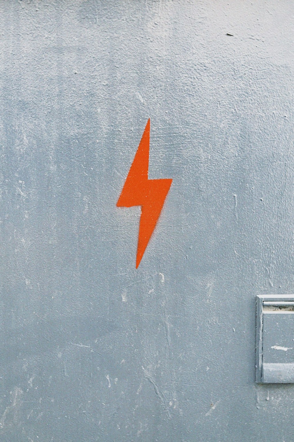 an orange lightning bolt painted on the side of a building