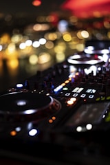 a close up of a dj controller with blurry lights in the background