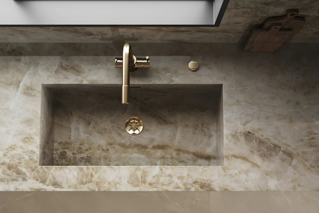 Basin carved into a cream and gold marble counter with a gold tap