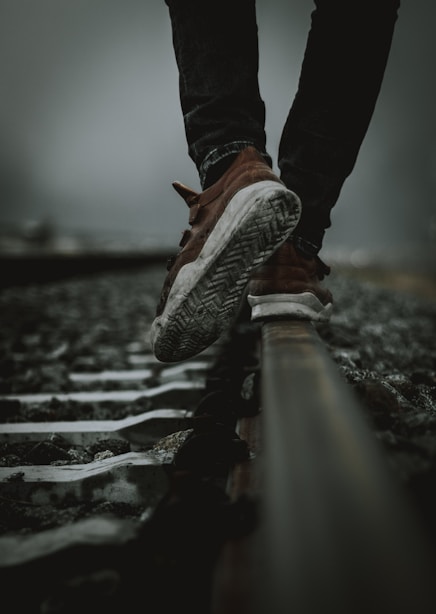 a person's feet on a rail in the rain