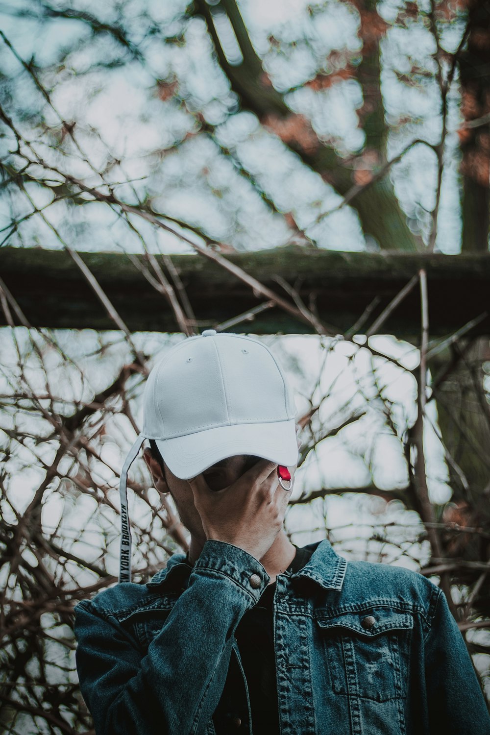 a man in a denim jacket and a white hat is talking on a cell phone