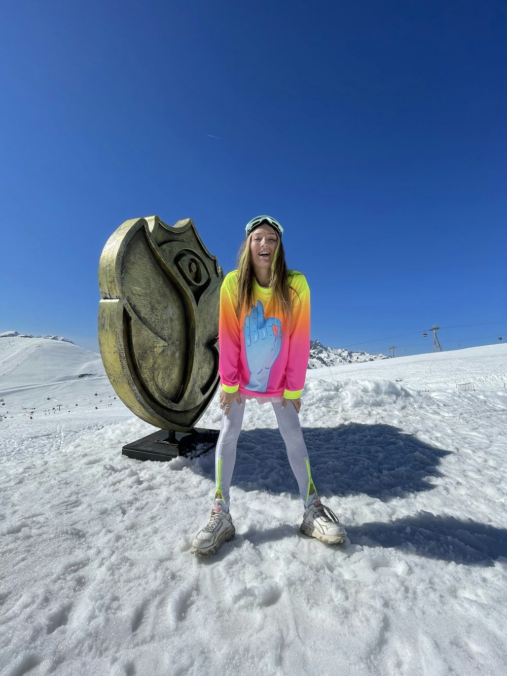 a girl poses in front of a statue of an eye