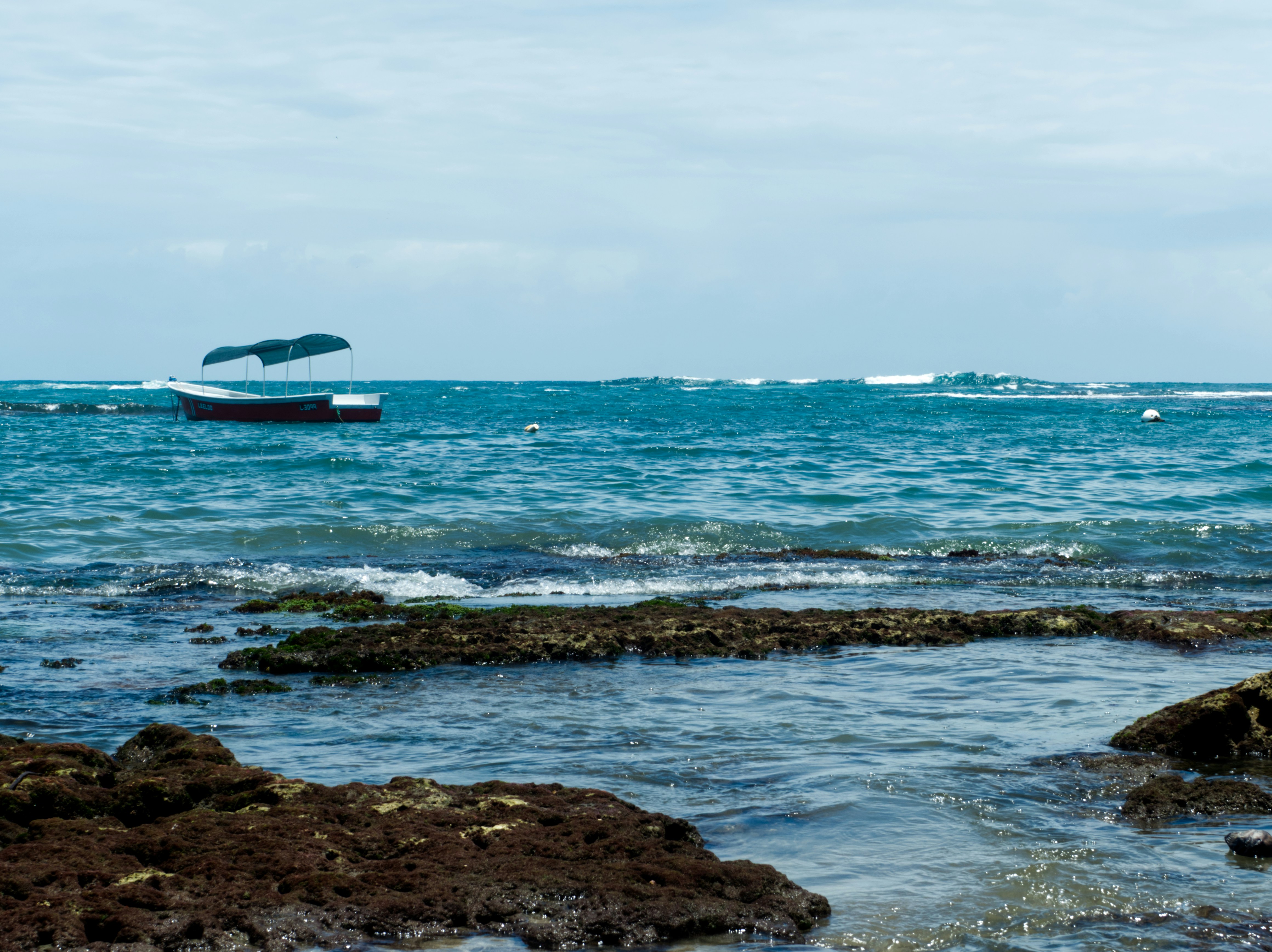 a boat in the ocean near a rocky shore