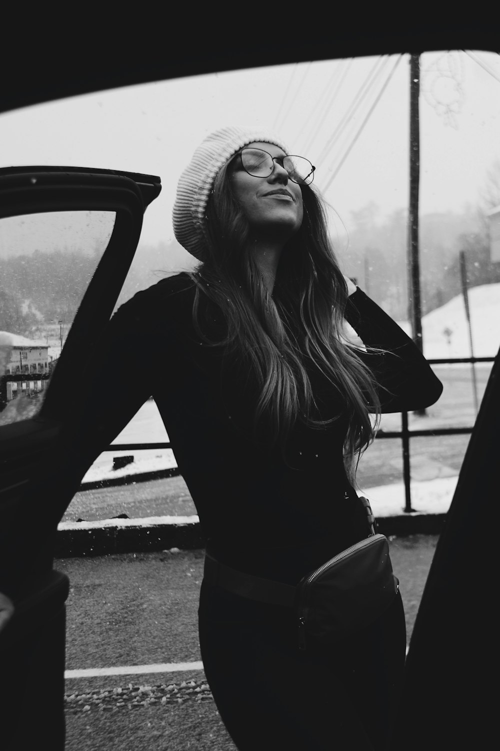 a woman standing next to a car wearing a hat