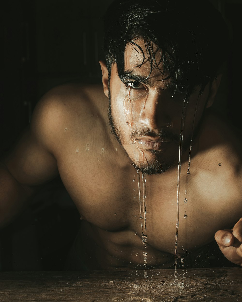 a shirtless man is drinking water from a faucet