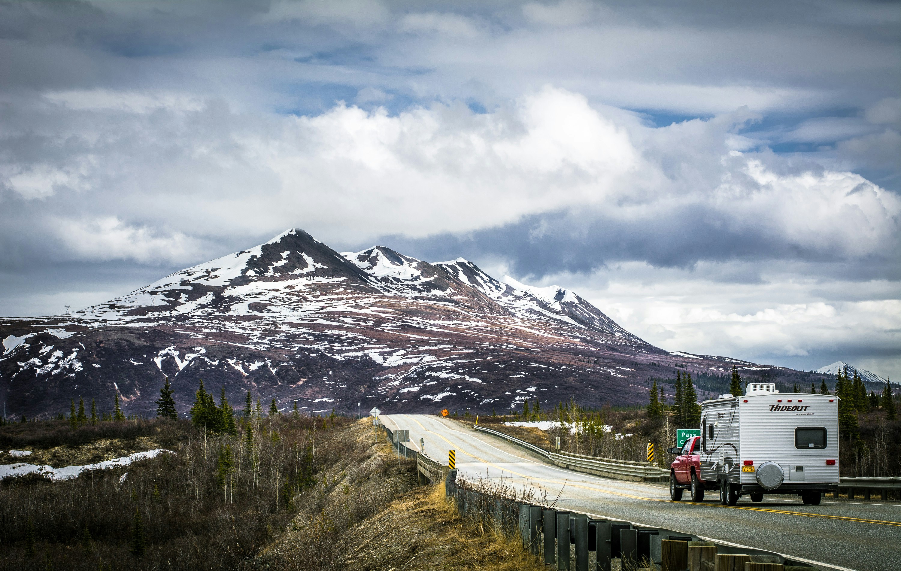a truck driving down a road with a mountain in the background