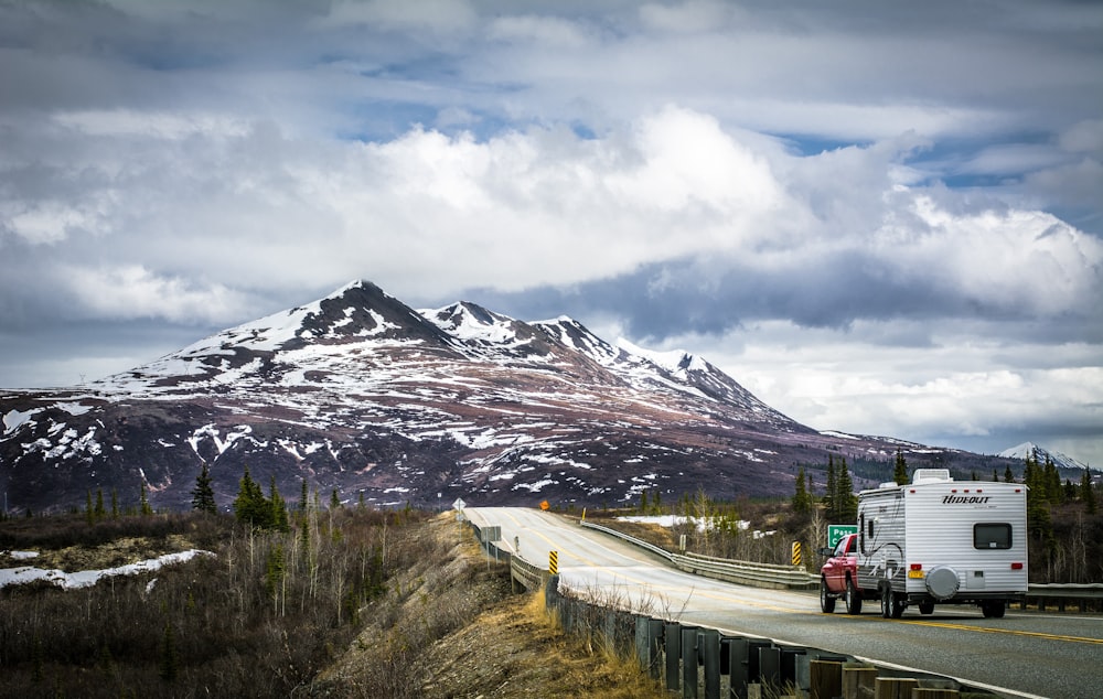 Ein Lastwagen, der eine Straße mit einem Berg im Hintergrund hinunterfährt