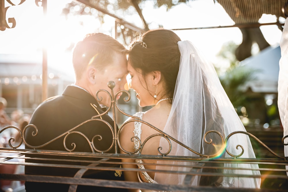a bride and groom kissing on a bench