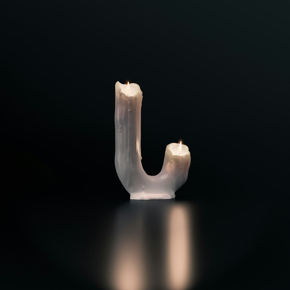 a lit candle in the shape of a letter j