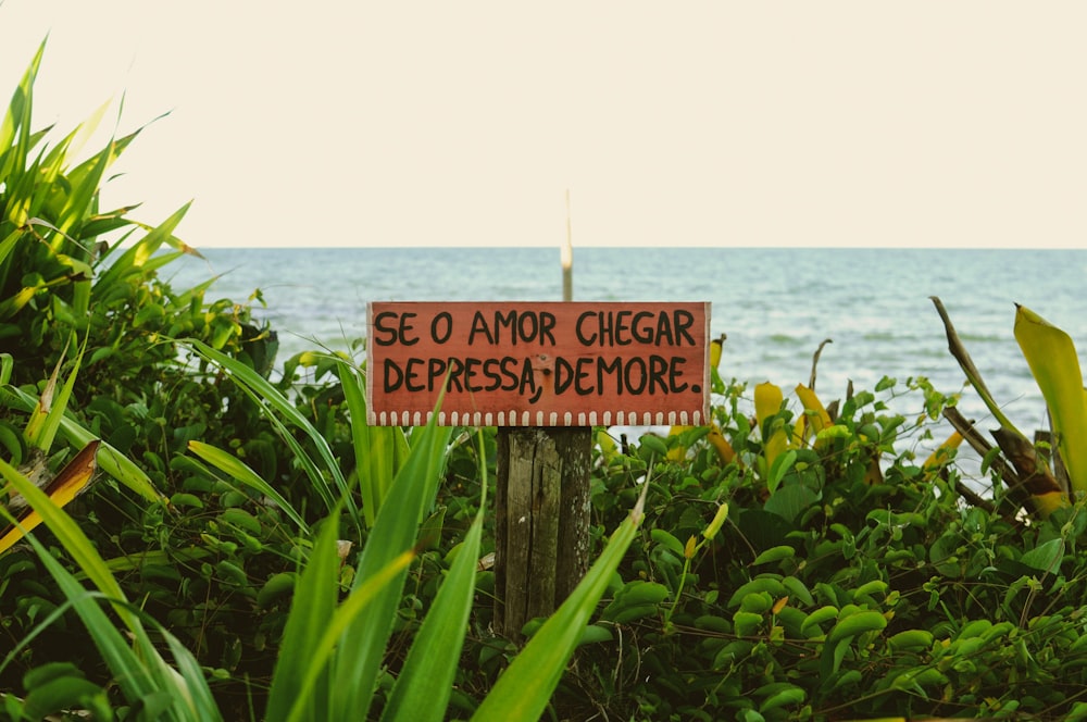 a sign on a wooden post in front of a body of water