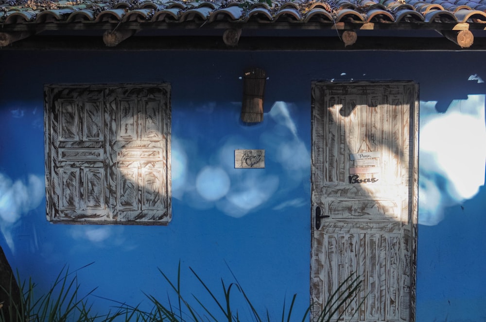 Ein blaues Haus mit zwei Holztüren und einem Ziegeldach