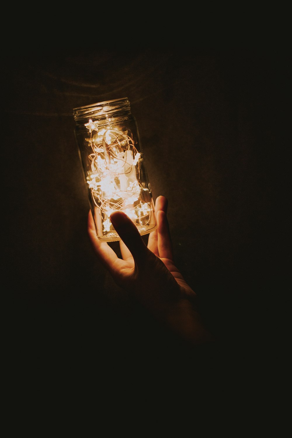 a person holding a lit jar in their hand