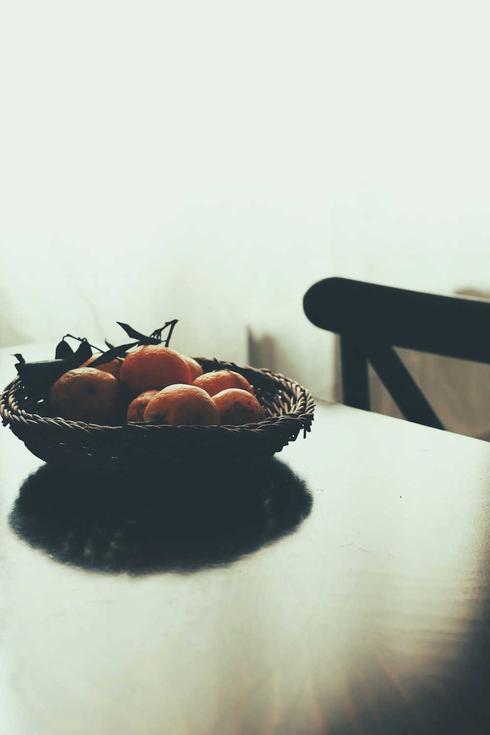 a basket of oranges sitting on top of a wooden table