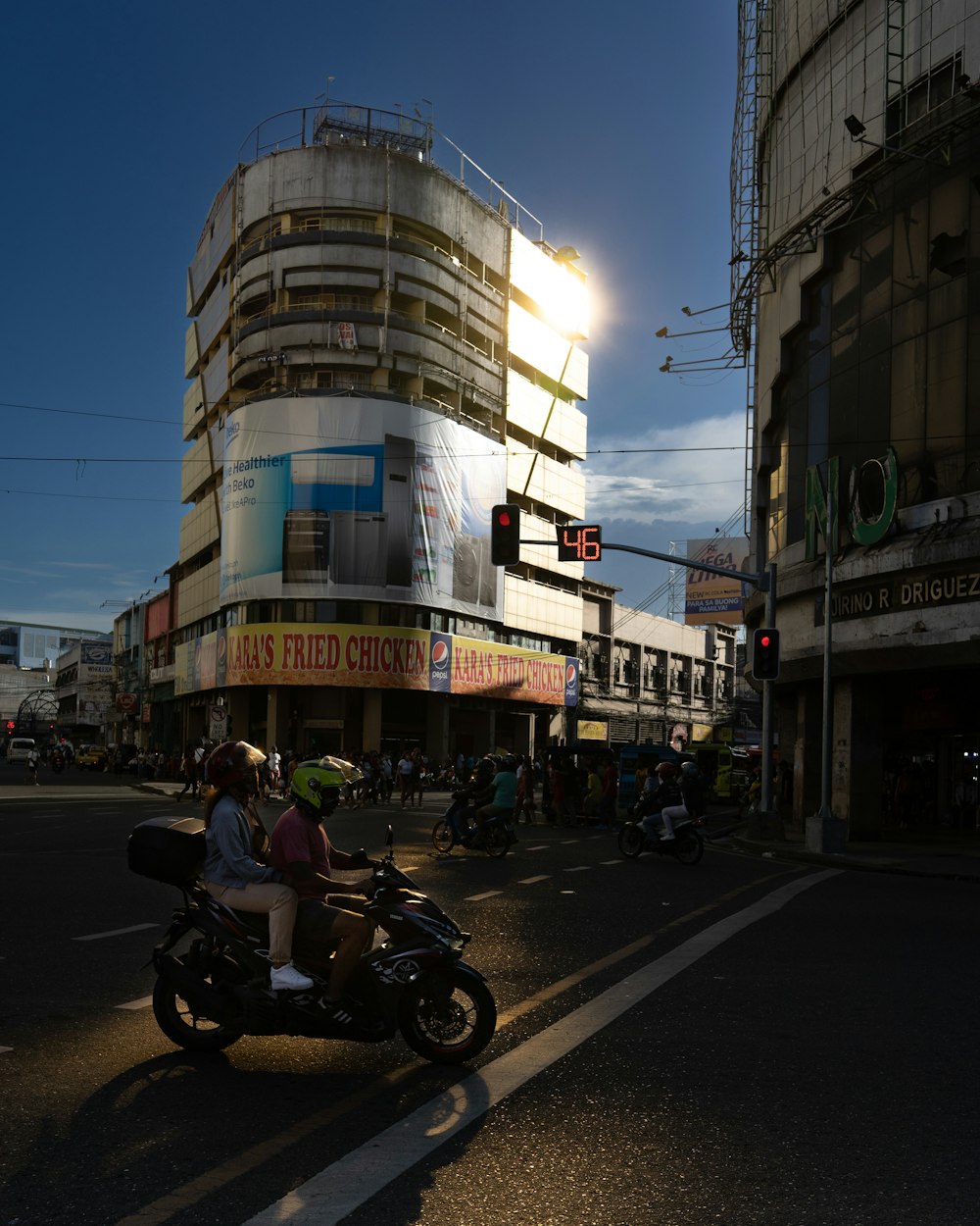 a man riding a motorcycle down a street next to tall buildings