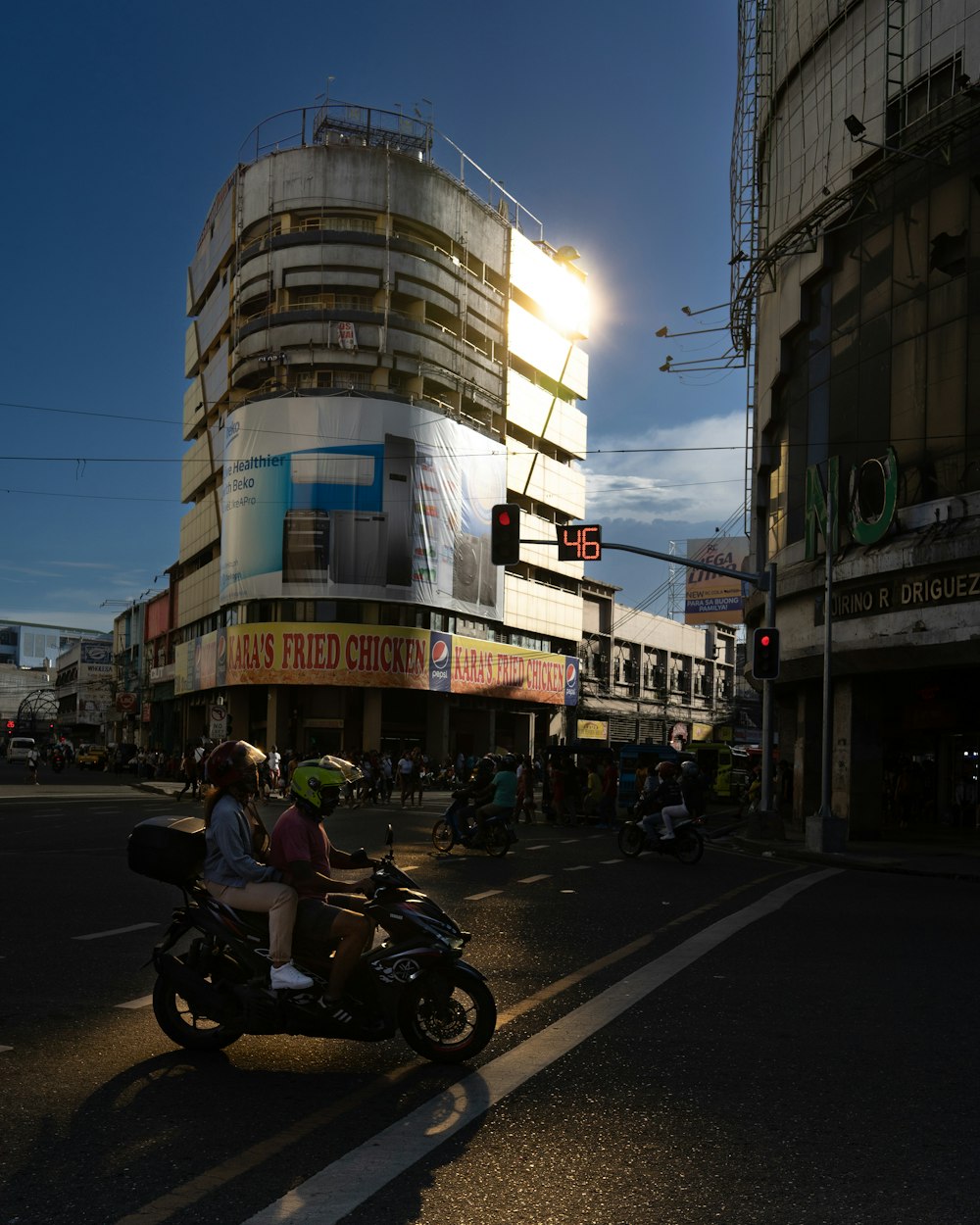 Un hombre conduciendo una motocicleta por una calle junto a edificios altos