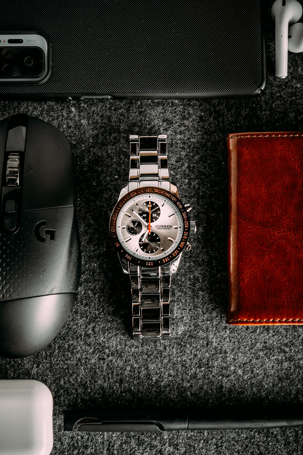 a watch sitting on top of a table next to a mouse