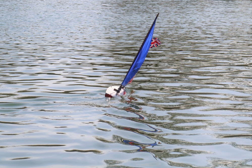 a small sail boat floating on top of a lake