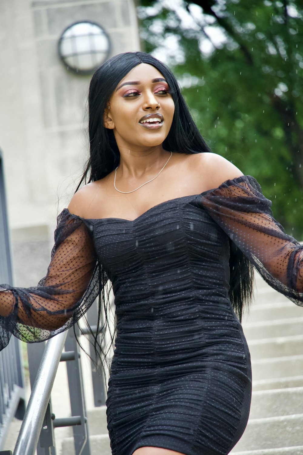 a woman in a black dress walking down a set of stairs