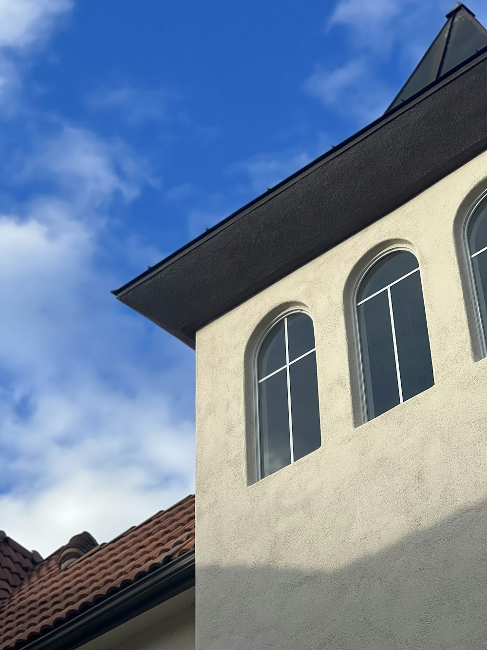 a white building with three windows and a sky background