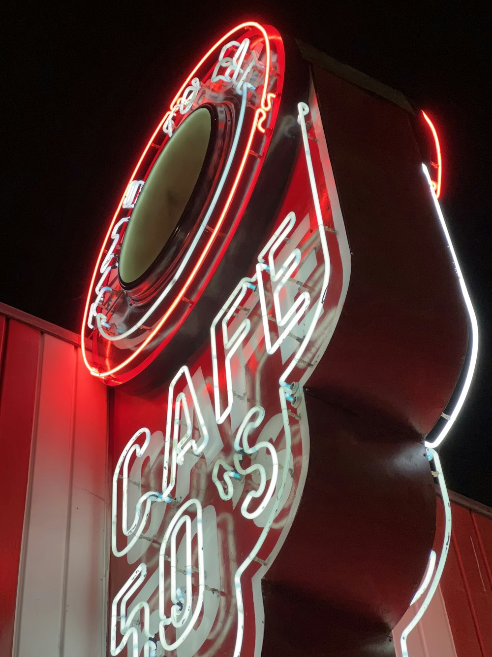 a red neon sign with a circular mirror on top of it
