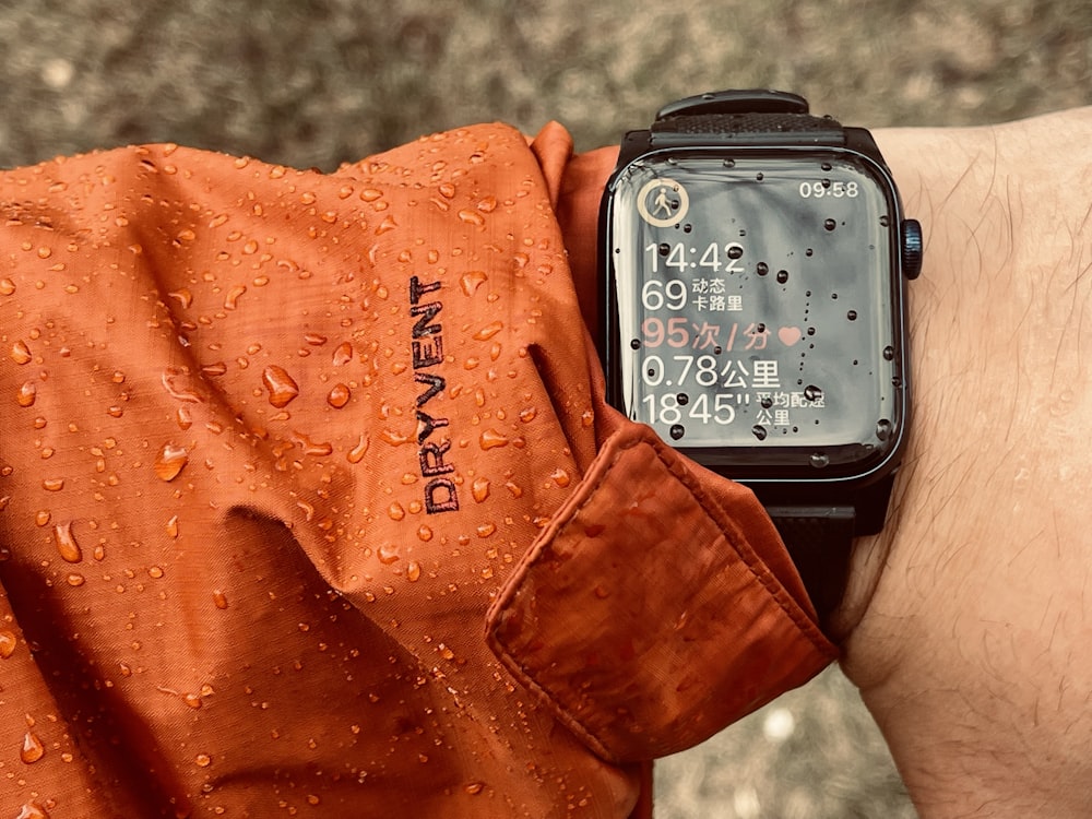 a person wearing an orange shirt and a black watch