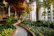 An outdoor garden pathway paved with soft stone slabs, surrounded by lush greenery and soft lighting.