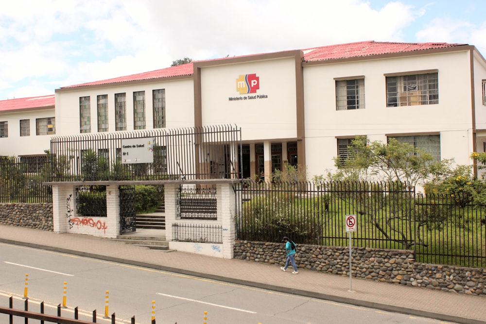 Un edificio blanco con un techo rojo al lado de una calle