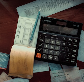 a calculator and invoice log on top of a wooden table