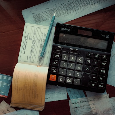 a calculator and invoice log on top of a wooden table