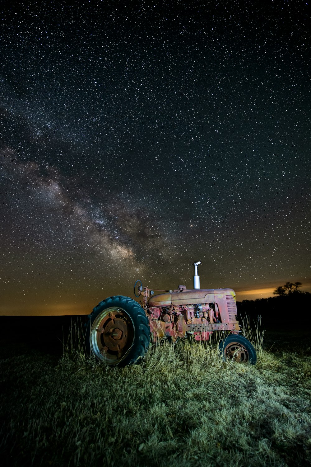 a tractor sitting in a field under a night sky