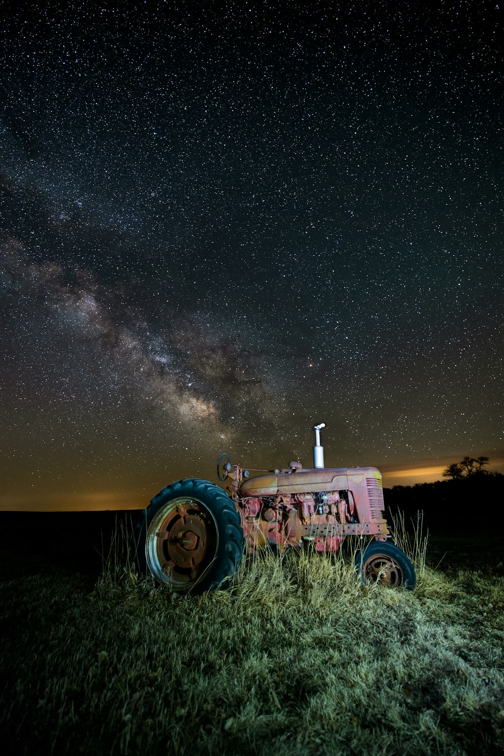 um trator sentado em um campo sob um céu noturno