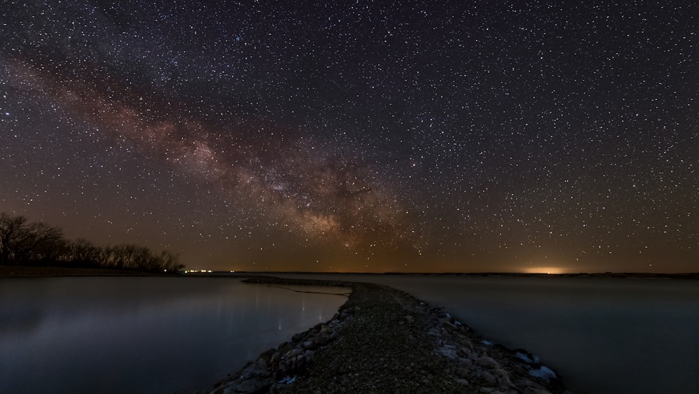 the night sky is filled with stars above a body of water