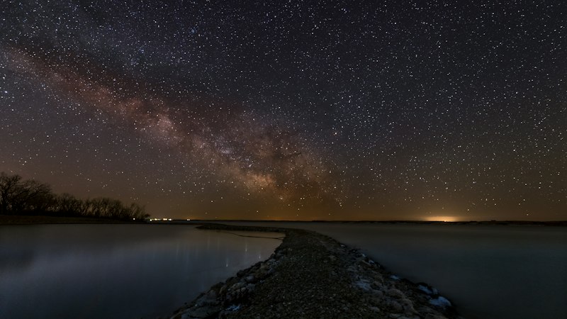 Night sky dense with stars and the Milky Way reflected in the still surface of a Nebraska reservoir