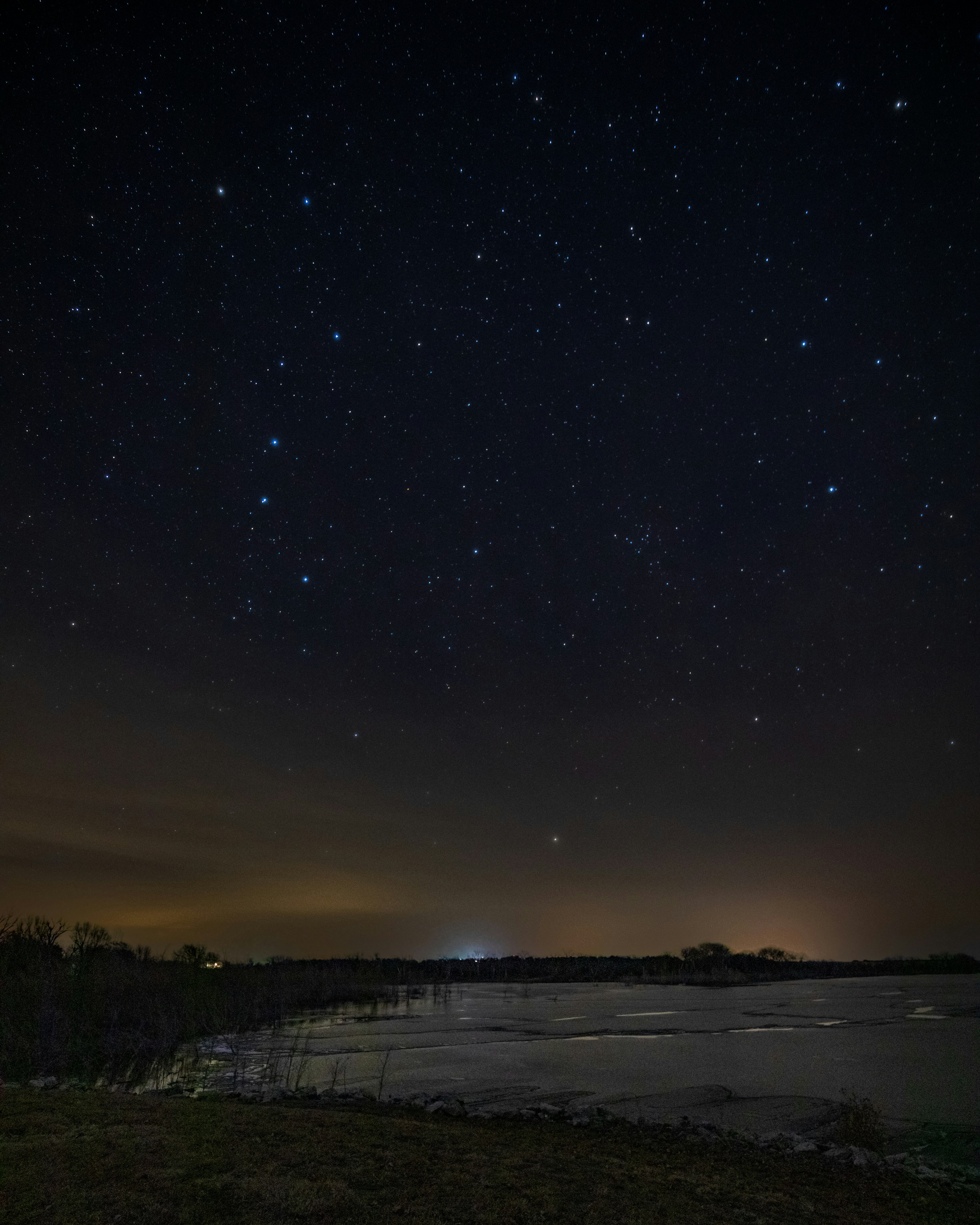 the night sky with stars above a body of water