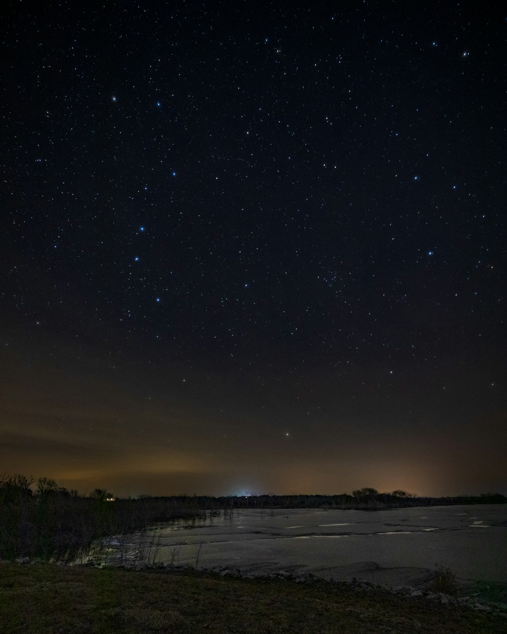 the night sky with stars above a body of water