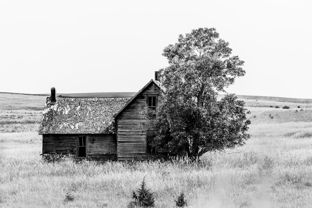 a black and white photo of an old house in a field