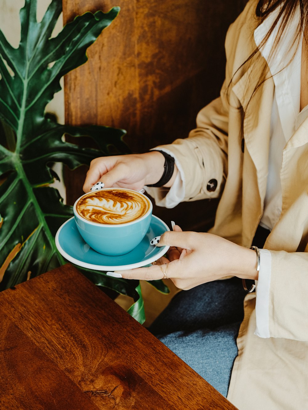 a woman sitting at a table with a cup of coffee