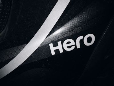 A close-up view of a black surface featuring a bold, white, stylized word 'Hero' with a white diagonal stripe running through the background. The surface has a subtle texture and glossy finish.