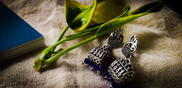 Handcrafted silver earrings shaped like moth wings resting on a vintage book.