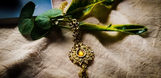 Artful close-up of gold jewelry resting on deep green silk fabric.
