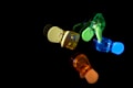 A group of colorful, translucent plastic clips arranged against a black background. They are illuminated from within, creating a glowing effect in shades of yellow, green, blue, and red.