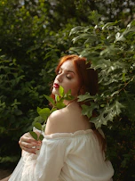a woman in a white dress holding a green leaf